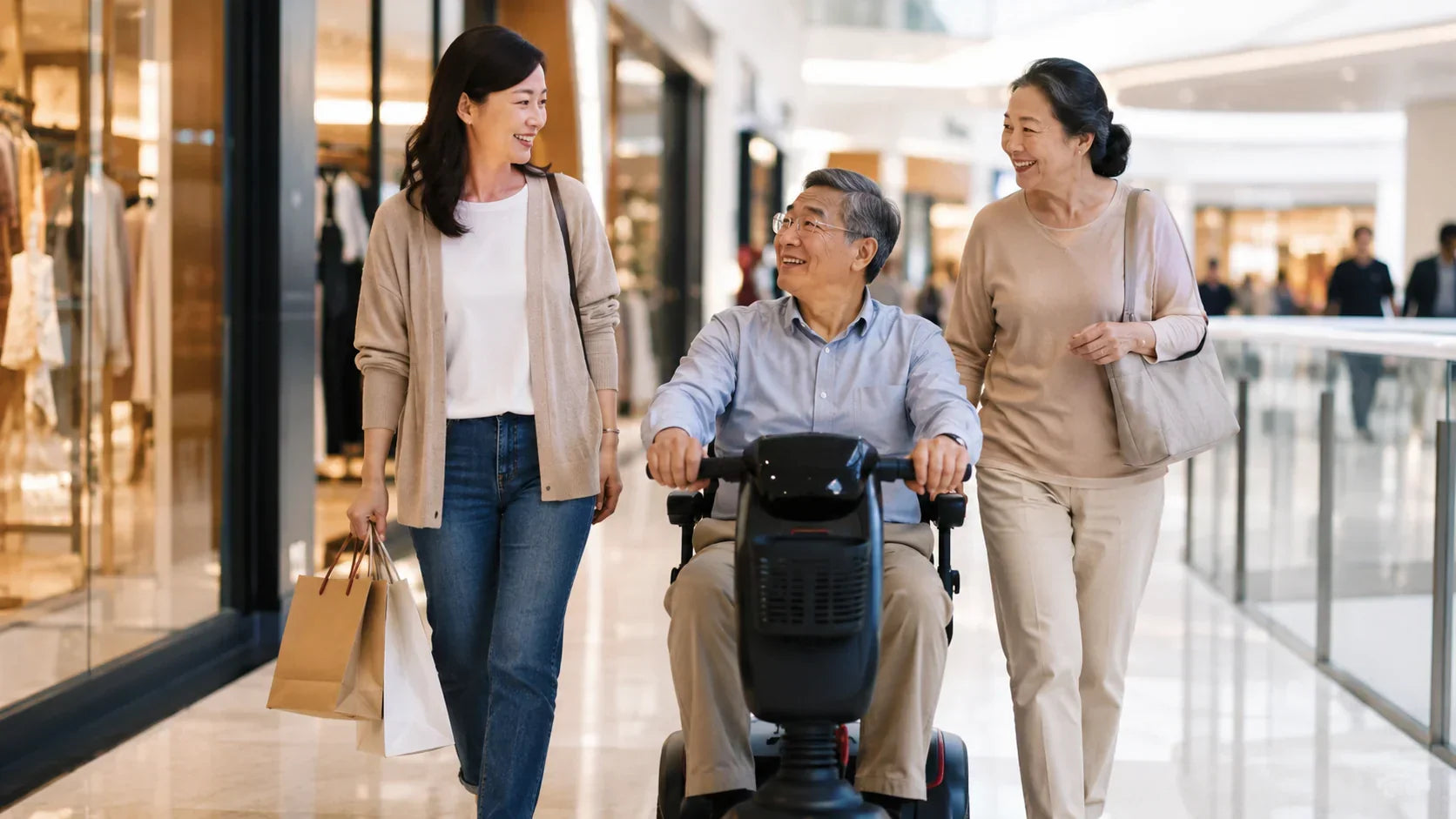 Asian family walking through a shopping mall with an older man using a mobility scooter, showing comfort, independence, and support from loved ones.