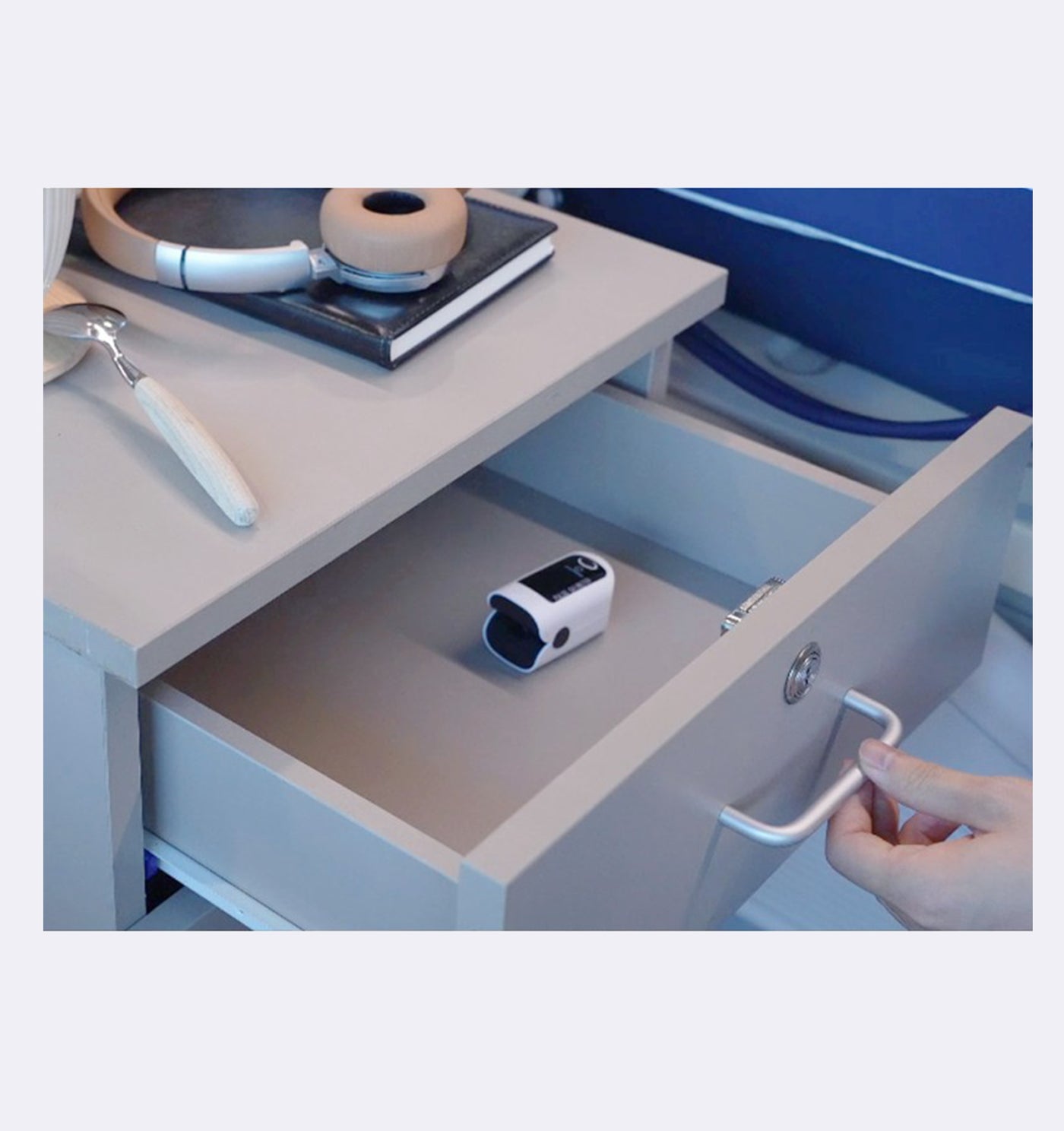 Hand opening a drawer to reveal a small electronic device on a kitchen counter.