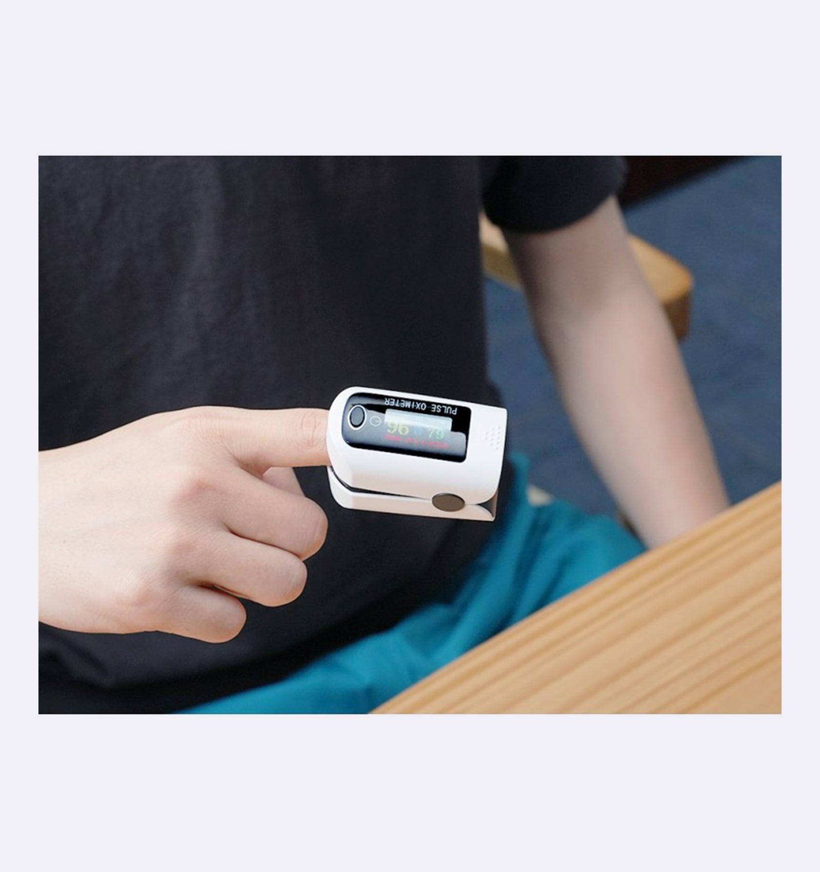 Person wearing a pulse oximeter on their finger with a blurred background