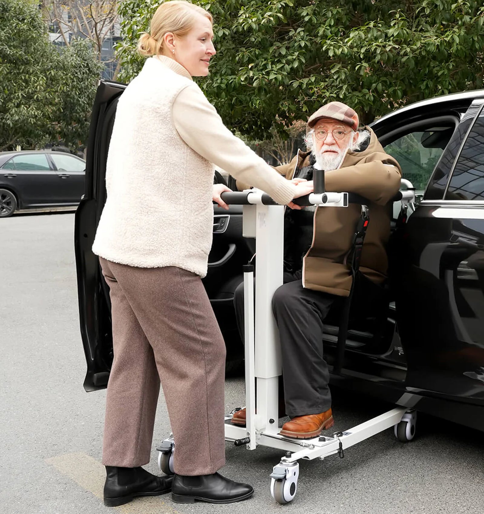 Person assisting an elderly person using a wheelchair lift to enter a car.