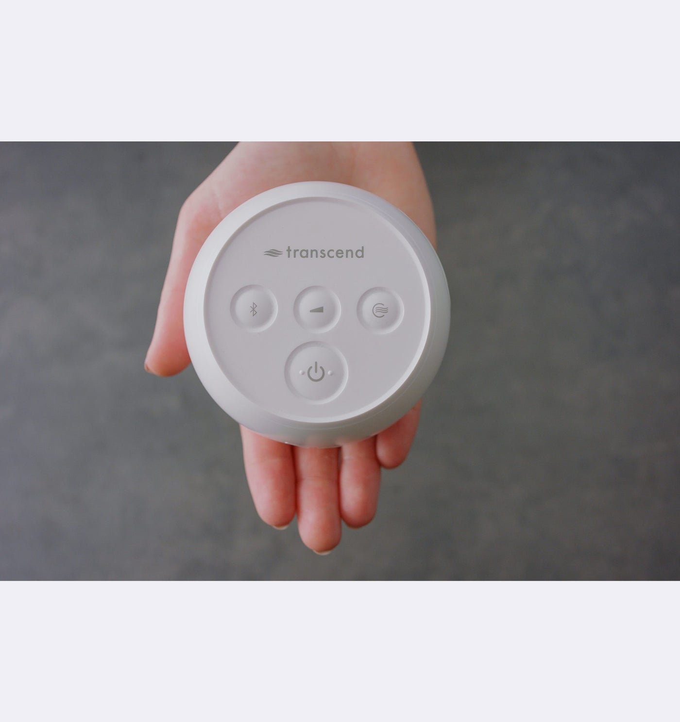 Hand holding a white device with 'transcend' branding against a gray background