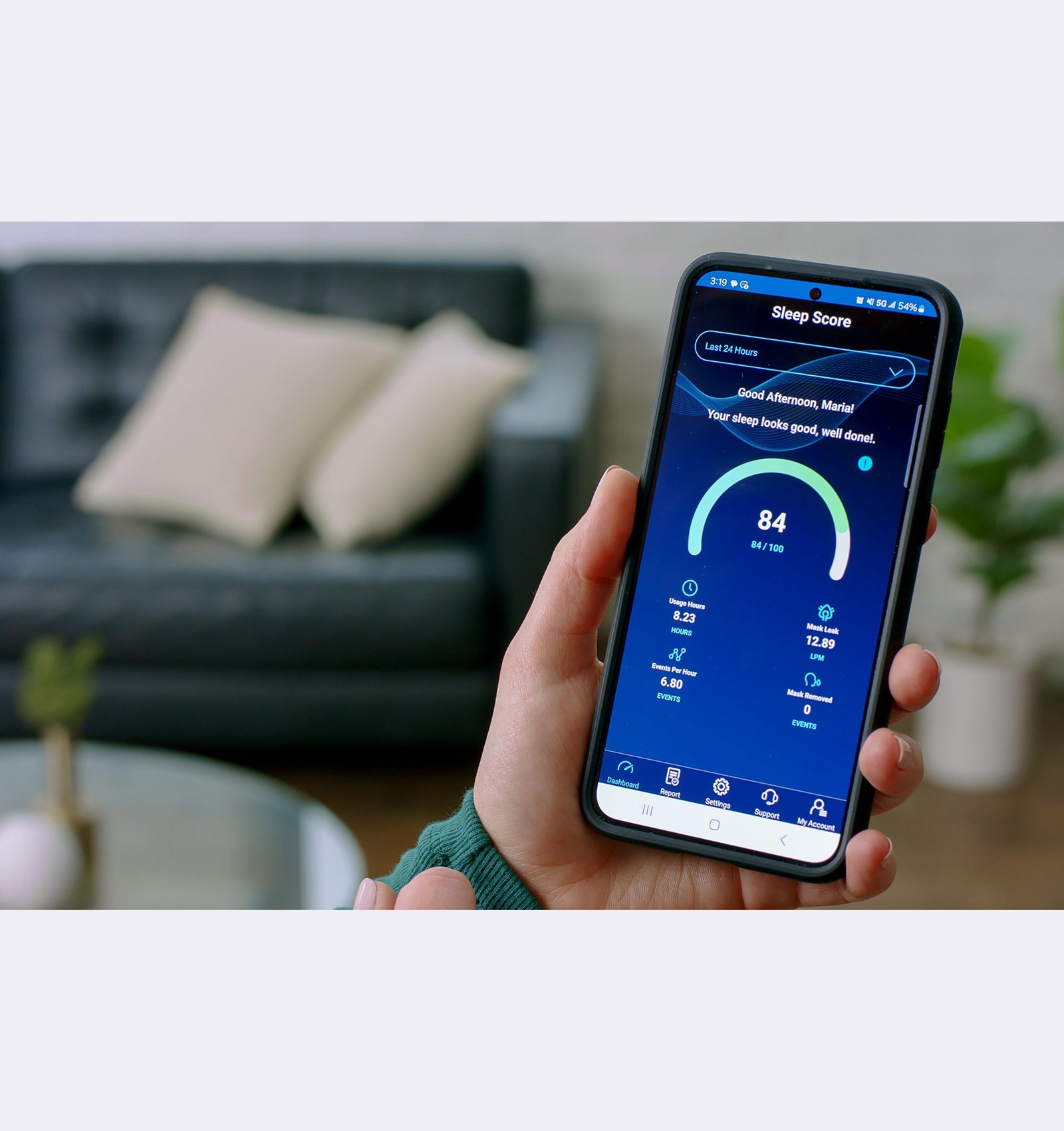 Person holding a smartphone with a sleep tracking app in a living room setting