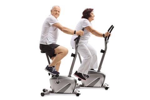 elderly couple riding stationary bikes