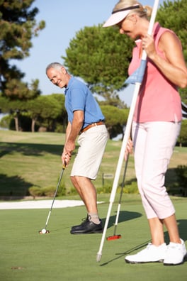 elderly couple playing golf